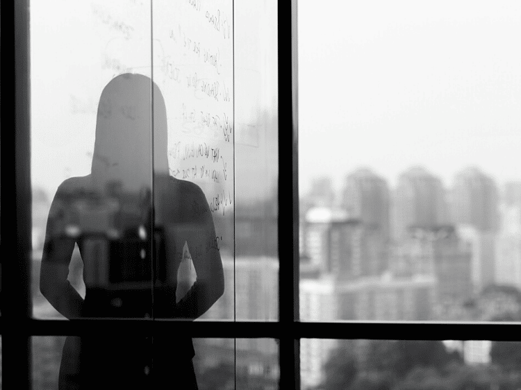 Silhouette shadow of woman looking at city from office