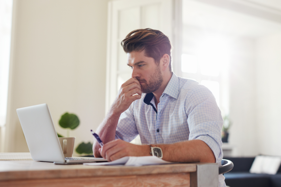 man in button down shirt sitting at table in front of laptop