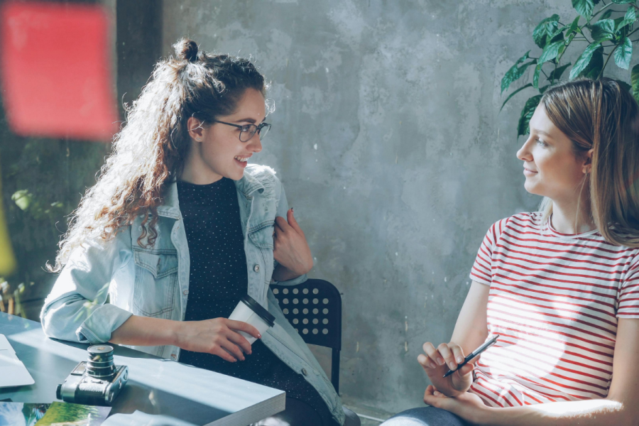 two women talking casually in an office setting