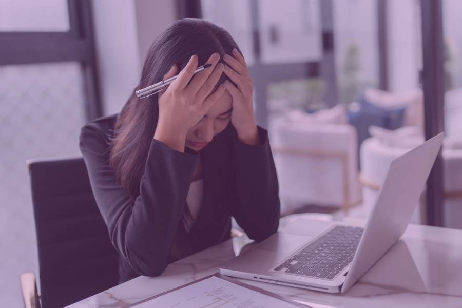 woman with her head in her hands in frustration sitting in front of her laptop