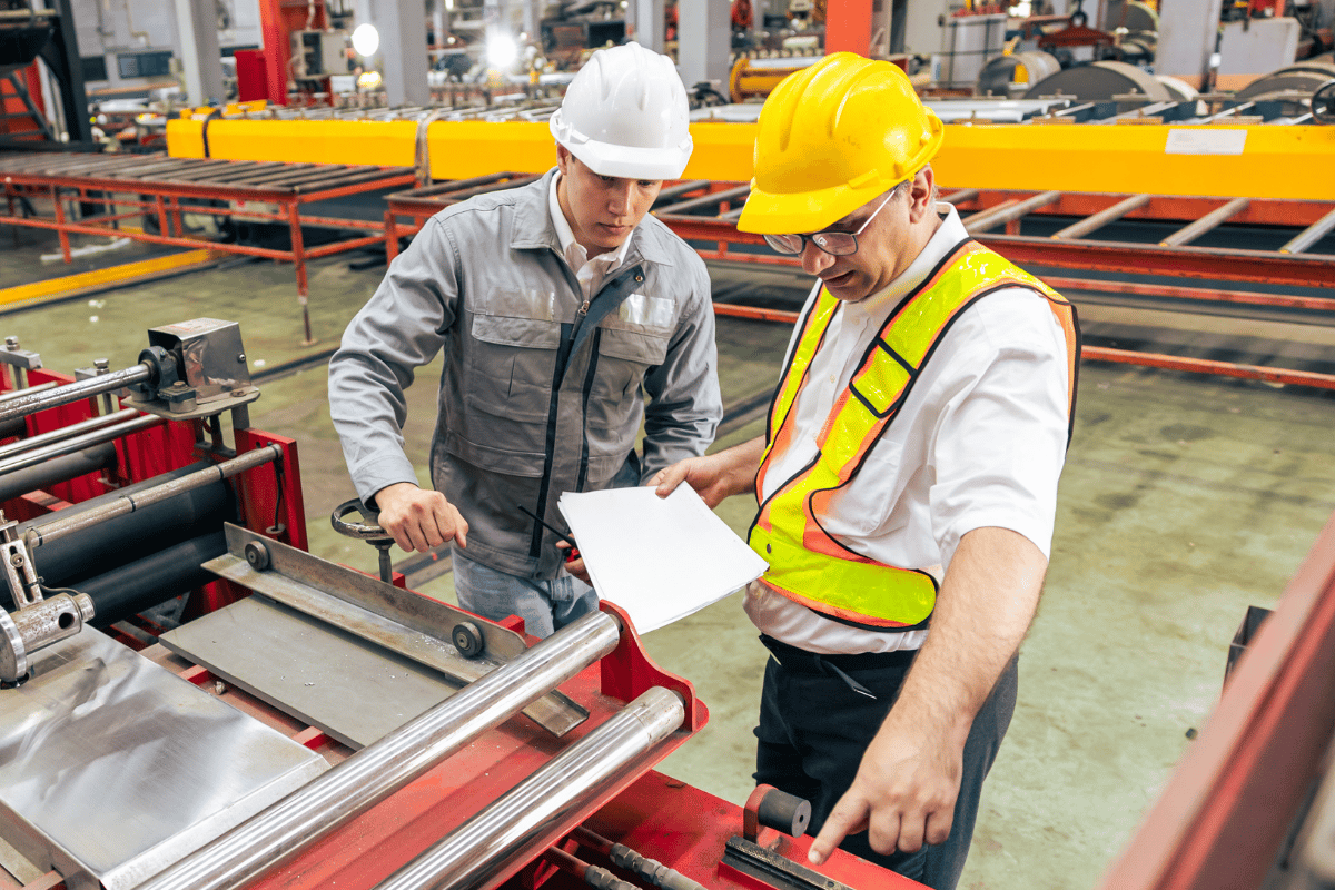 Supervisor and worker in a warehouse working together with machinery.