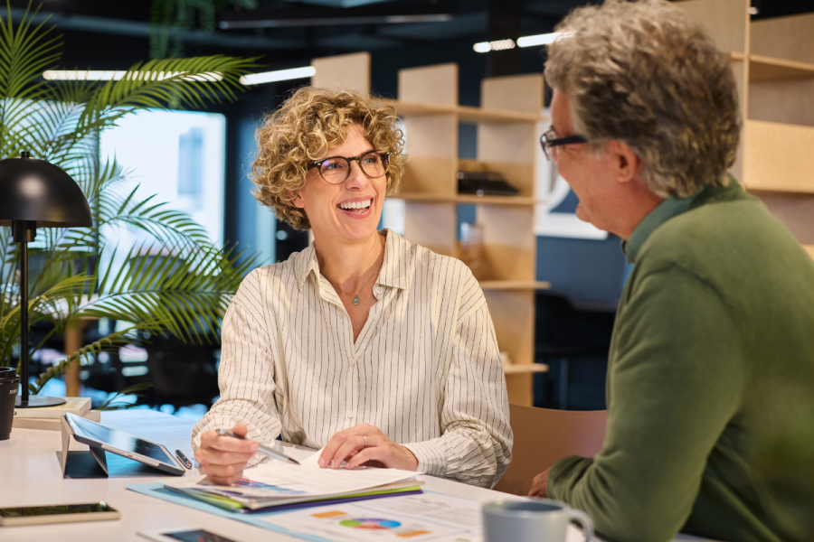 two colleagues at work have a productive conversation and smile.