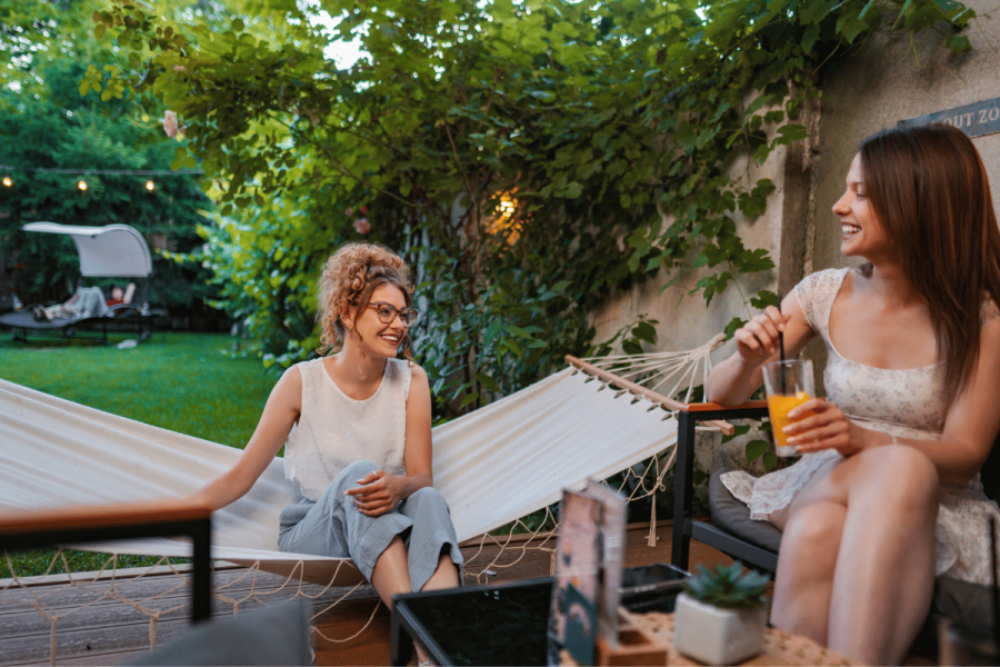 two women have a conversation in a backyard during summertime