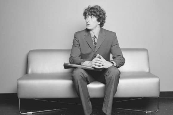 Young job seeker, wearing a suit, waiting nervously for his interview.