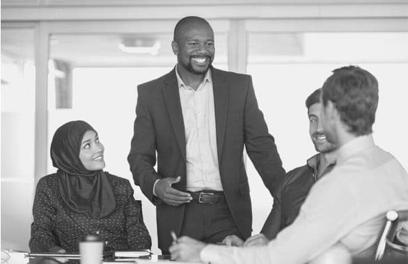 A diverse group of colleagues talking and laughing together at the office.