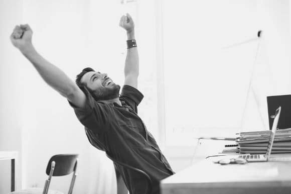 A self-motivated employee, raising his arms and stretching after completing a difficult task.