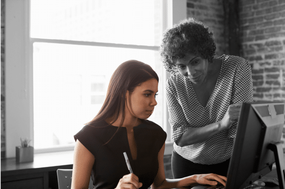 An older woman mentors a younger one at work