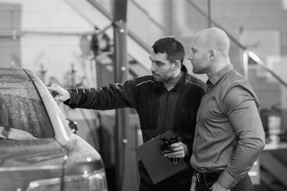 A worker in a garage is showing something to a customr.