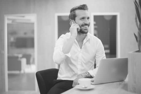 Director of operations, sitting at his desk with a cup of coffee, talking on the phone.