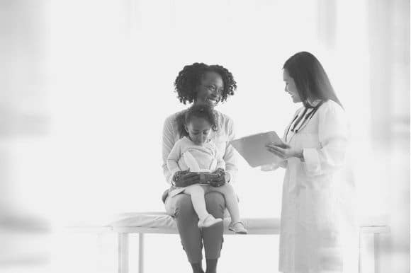 Paediatrician talking with parent and child in office