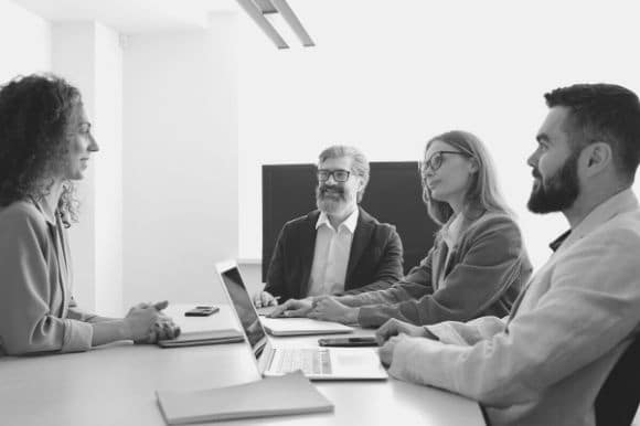 A team of recruiters talking around a table, trying to improve recruitment strategies for their company.