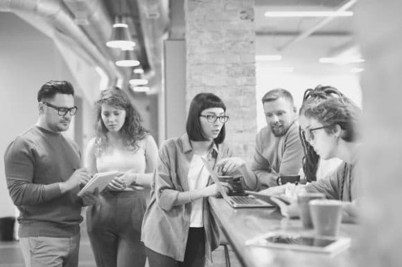 Determining job market value is an important step in determine salary ranges. This is a picture of six employees standing by the reception desk.