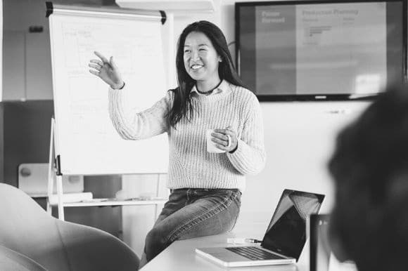 An effective manager addressing her staff while holding a cup of coffee.