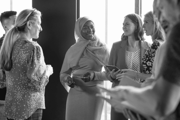 A diverse group of new employees mingle with a hiring manager on their first day.