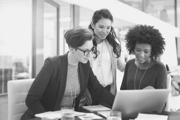 Three employees meeting together at a desk.