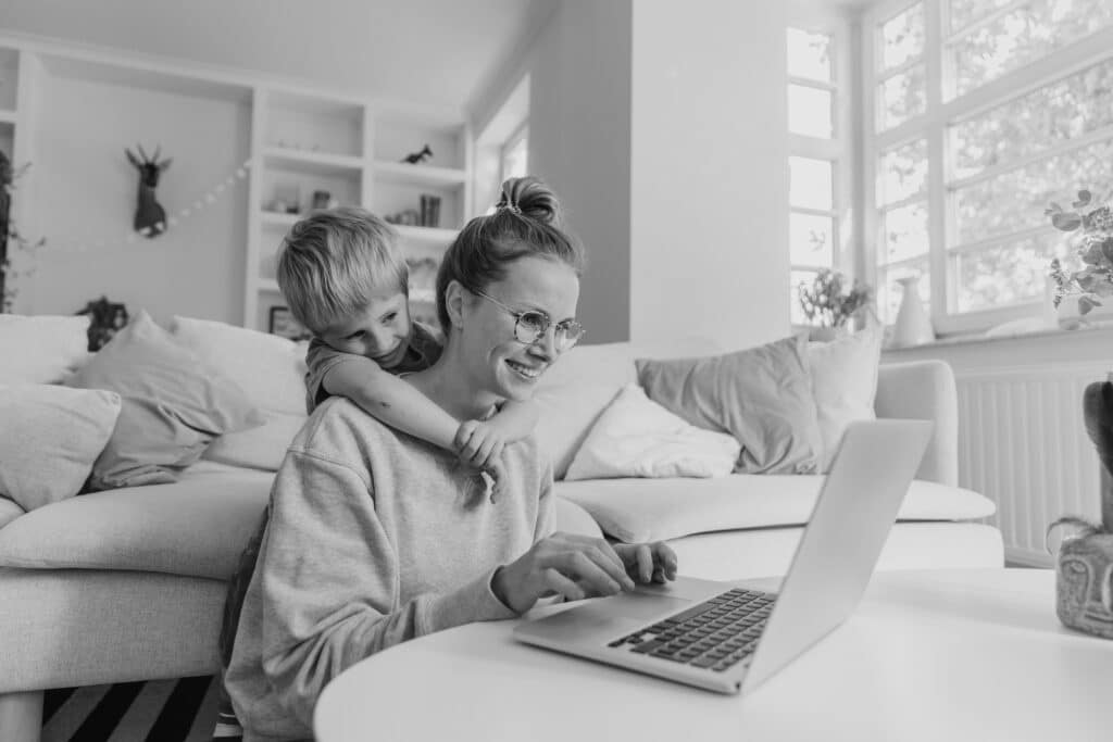 Mutter arbeitet zuhause und Sohn schaut zu.