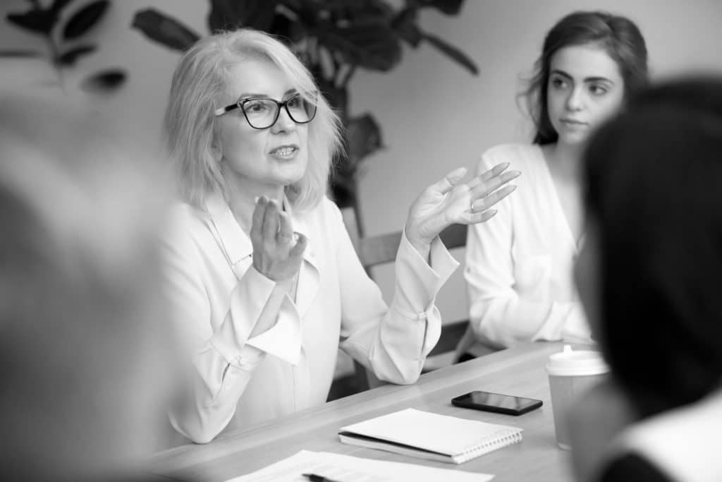 Frau mit Brille während eines Meetings.